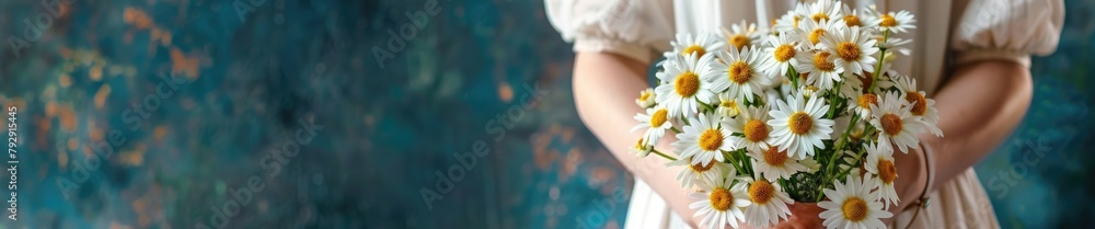 Fototapeta premium A woman holds a fresh, sunlit bouquet of daisies