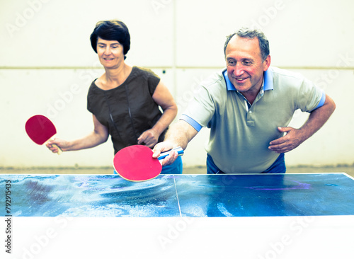 Happy mature spousesn playing table tennis