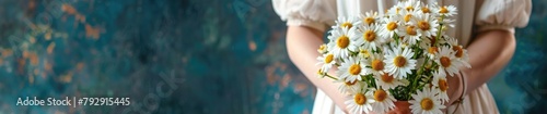 A woman holds a fresh  sunlit bouquet of daisies