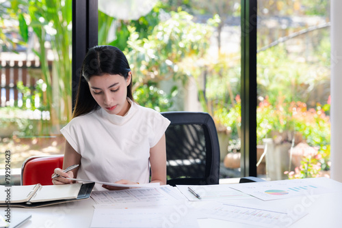Young businesswoman working with documents in office. Businesswoman holding papers preparing report analyzing work results.