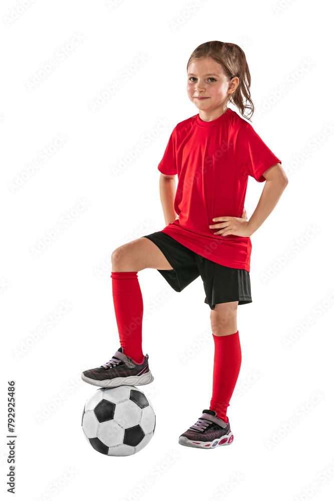 Portrait of girl, child, football player in red uniform training, posing against transparent background. Sportive and active kid. Concept of action, team sport game, energy, vitality.