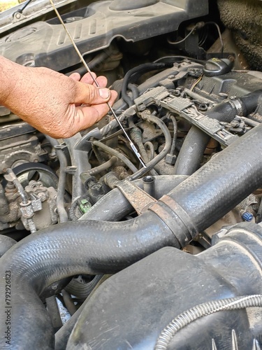 a man repairs a car by checking the oil level with a dipstick