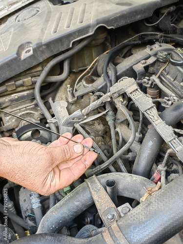 a man repairs a car by checking the oil level with a dipstick