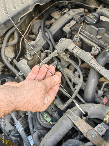 a man repairs a car by checking the oil level with a dipstick