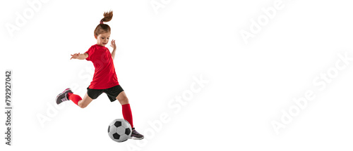 Portrait of athletic  fit child  girl in red uniform playing  training pass technique against transparent background. Sportive and active kid. Concept of action  team sport game  energy  vitality.