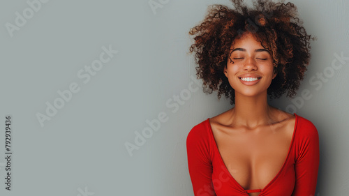 Afro woman in red halter V-Neck smiling isolated on gray photo