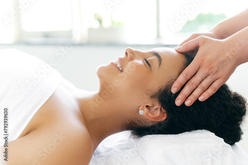 Wallpaper Mural Female massage therapist doing general forehead massage to a pretty girl. Side-view on calm relaxed smiling brazilian or hispanic woman lies on a massage table in a salon during a forehead massage Torontodigital.ca