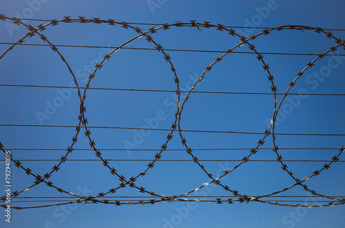 Barbed wire fence against clear blue sky. photo