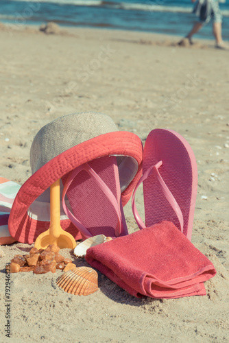 Different accessories for relax on sand. Straw hat, slippers and towel. Summer time on beach