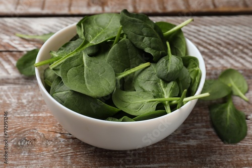 Fresh spinach leaves in bowl on wooden rustic table, closeup