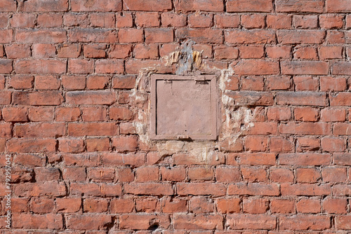 Square small hatch in a old brick wall