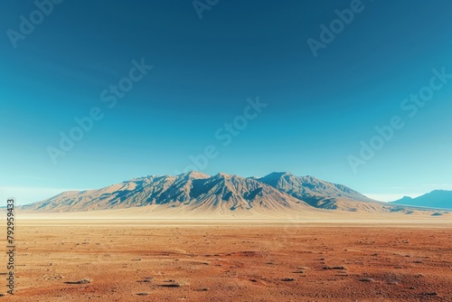A serene desert landscape with vast plains leading up to a majestic mountain range under a clear blue sky.