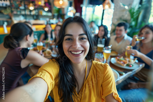A woman in a yellow shirt is smiling at the camera while sitting at a table with