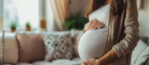 Serene pregnant woman holding her belly gently, standing in a cozy home setting.