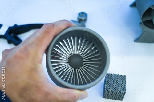 man hand holding model of an jet engine made of plastic on a 3d printer