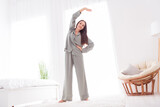 Photo of cheerful charming lady wear grey pajama enjoy weekend doing morning stretching indoors house bedroom