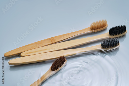 Natural bamboo toothbrushes in water on a blue background.