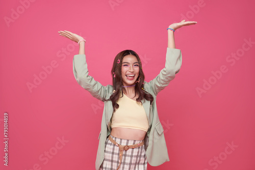 Happy Asian woman presenting or showing open hand palm with copy space for product isolated on pink background