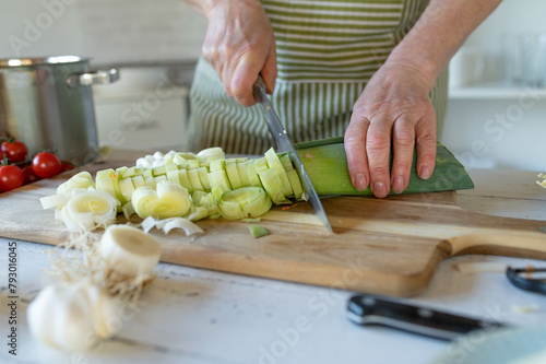 Cutting leek on a cutting board by woman´s hand