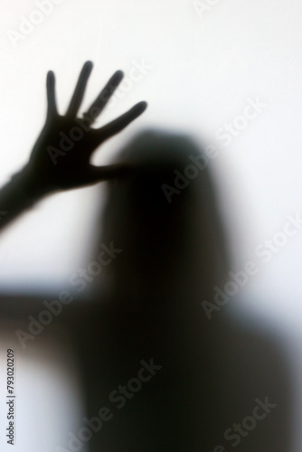Silhouette of a woman behind the glass. Stop violence and sexual abuse against women. Melancholy and crisis concept.
