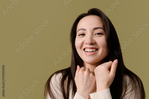 Portrait of happy young asian woman looking at camera isolated on green 