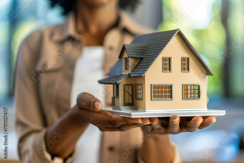 A real estate agent holds up a model home, real estate sales and real estate services 