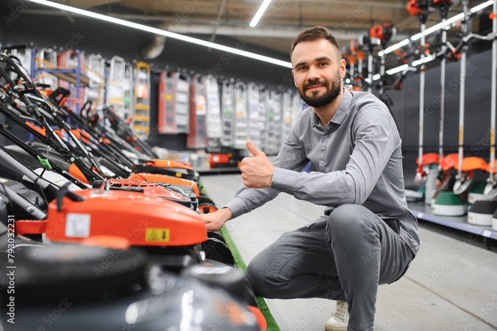 Young man buys a new lawnmower in a garden supplies store