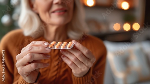 A senior woman is holding a blister pack of pills.