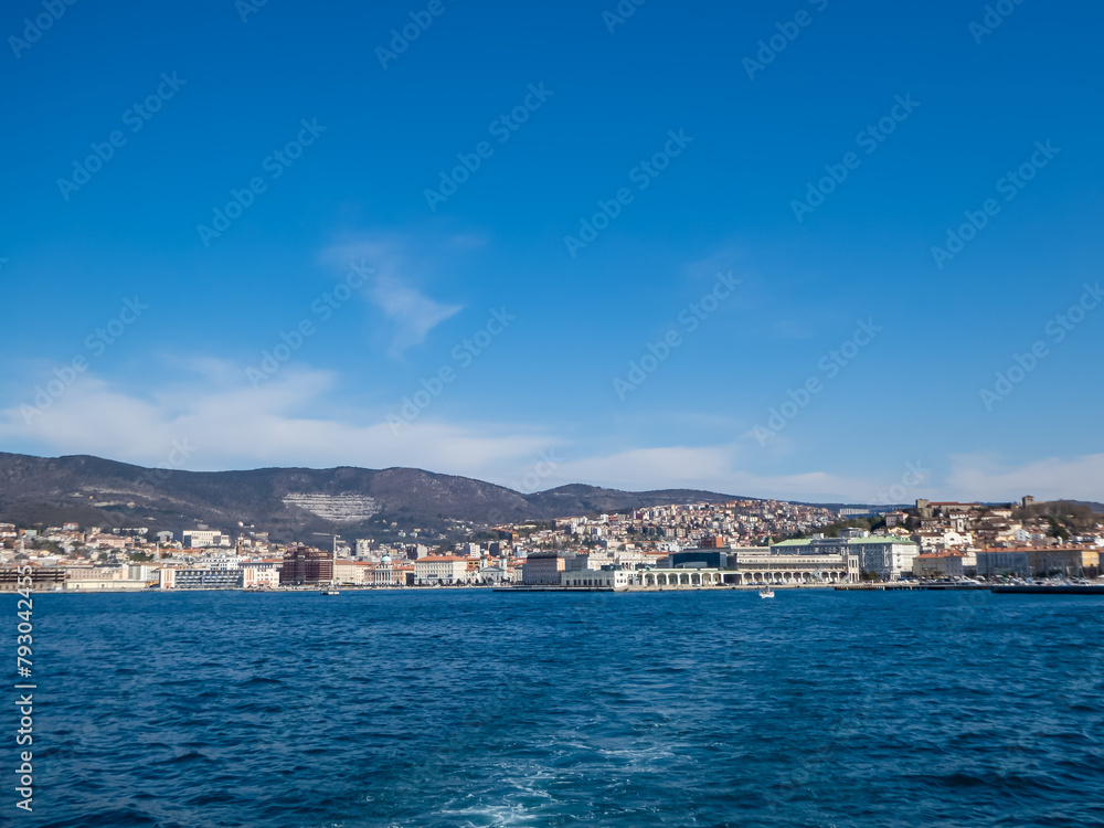Scenic view from a ferry of the port of Trieste from in Friuli-Venezia Giulia, Italy, Europe. Blue sky in tranquil atmosphere at Adriatic Mediterranean sea in summer. Boat tour along the coastline
