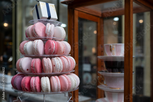 Delicious macarons in soft pastel shades are piled on a plate in a market stall. Blurred background