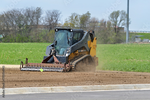 Track skid steer multi terrain loader landscaping an area for grass seeding