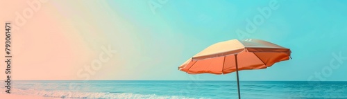 An orange beach umbrella sits on a sandy beach with the ocean in the background.