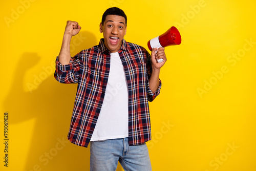 Portrait of overjoyed guy wear checkered shirt hold loudspeaker scream yeas support football team isolated on vivid color background photo