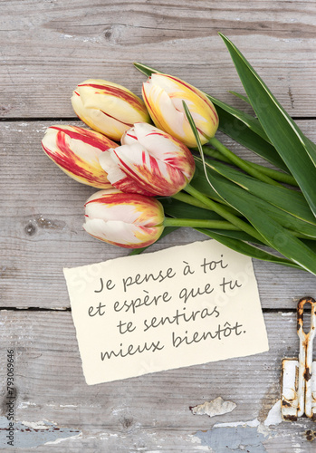 Greeting card with red, yellow and white tulips and French text: I'm thinking of you. I hope you feel better soon