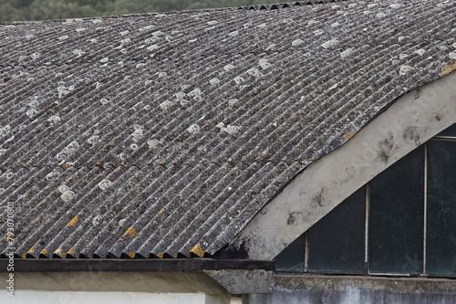 Old aged and damaged dangerous roof made of prefabricated and wave-shaped panels with wooden structure - Asbestos fibers can be released into the air and be breathed in - they cause lung cancer