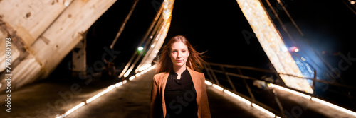 portrait of a woman walking on a bridge by night photo