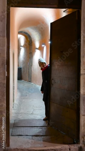 Lyon, France, December 27, 2023. Vertical night footage of an access door to Lyon's traboules: the characteristic covered walkways. A middle-aged woman closes the door. photo