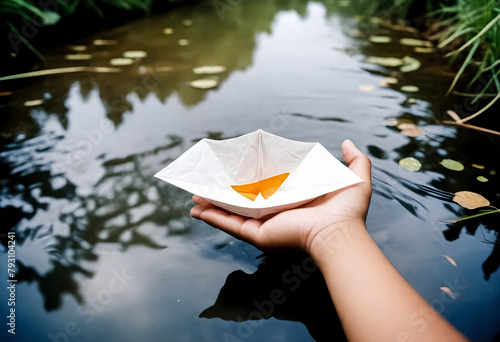 a person holding a paper boat on the water