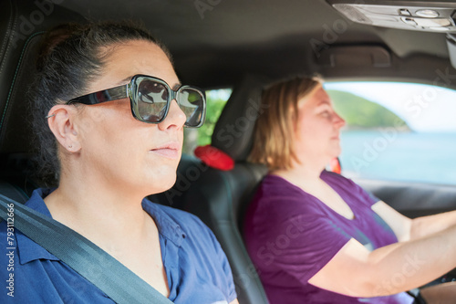 Two adult women travel by car on a coastal route during the summer holidays.