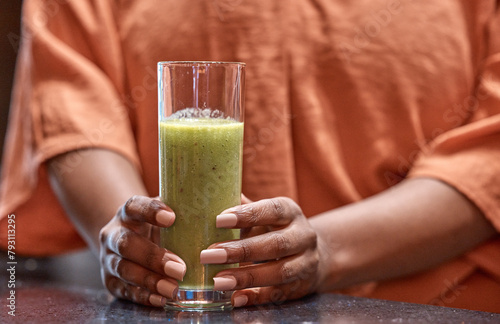Hands, drink and woman with smoothie in home for healthy diet, nutrition or wellness at table in kitchen in the morning. Glass, organic or green juice for vegan cocktail, detox or breakfast closeup