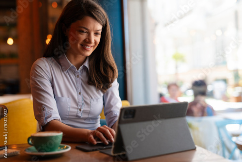 Woman sitting in coffee shop and using tablet to write