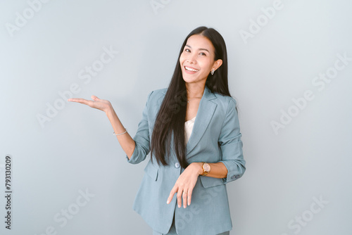 Portrait of beautiful Asian businesswoman presenting or showing open hand palm with copy space for product isolated green pastel background