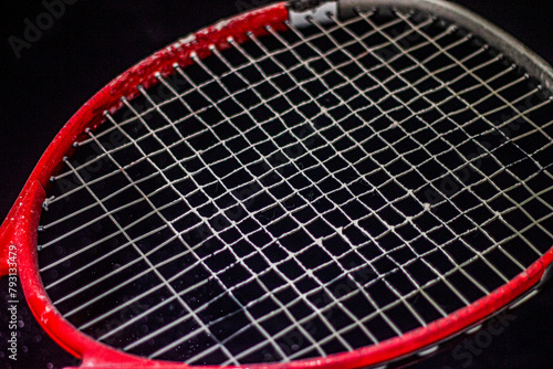 Big red tennis racket close-up on a black background