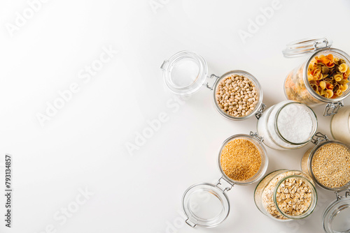 food storage, culinary and eating concept - close up of jars with different cereals, pasta and beans on white background, top view