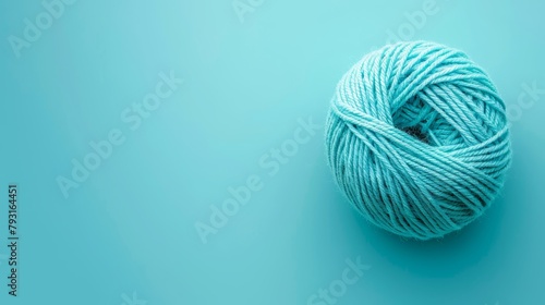   A ball of yarn sits atop a light blue surface, featuring a white yarn ball in its center