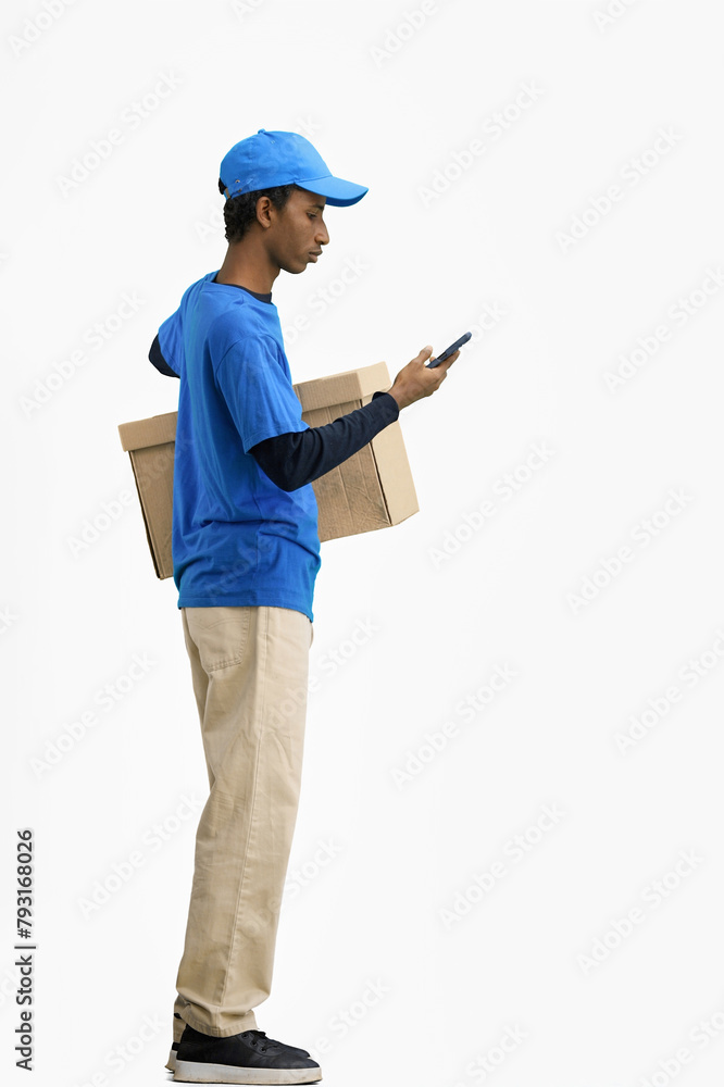 The deliveryman, in full height, on a white background, with a box, talking on the phone The deliveryman, in full height, on a white background, with a box, talking on the phone