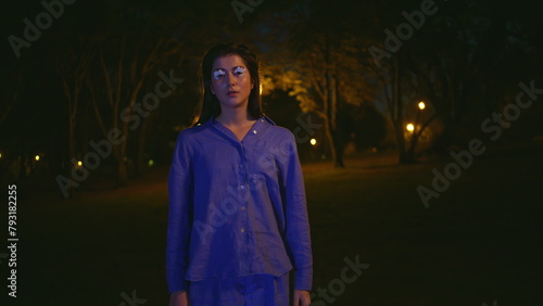 Mysterious woman standing solitude illuminated by park night lanterns closeup © stockbusters