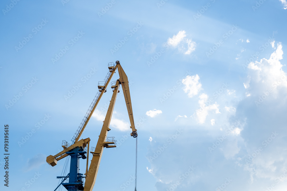 Industrial cranes reach up to a sunlit sky with billowing clouds, a stark contrast of man made machinery and the grandeur of nature, suitable for infrastructure projects. Industrial cranes reach up to a sunlit sky with billowing clouds, a stark contrast of man made machinery and the grandeur of nature, suitable for infrastructure projects.