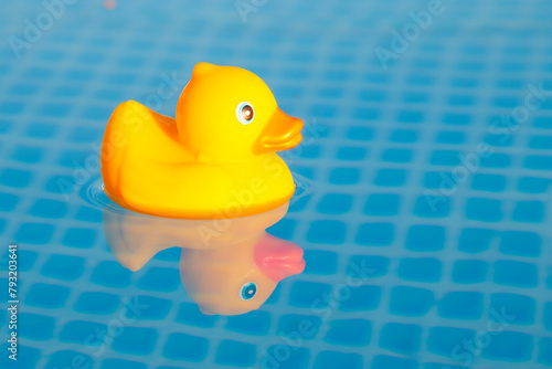 Summer vacation, the concept of a children's game. A small rubber yellow duck floats in water in the pool. Symbol of swimming, happy childhood,