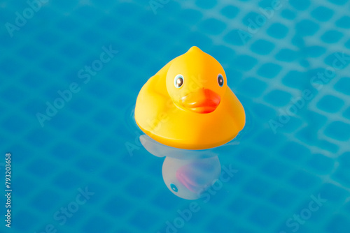 Summer vacation, the concept of a children's game. A small rubber yellow duck floats in water in the pool. Symbol of swimming, happy childhood,